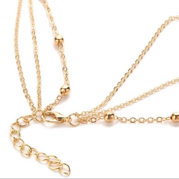 Close-up of a gold multilayer necklace chain with ball accents and clasp detail, showcasing its quality and design.